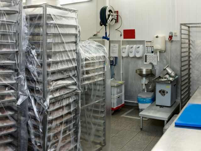 in einem Lagerraum einer Großbäckerei stehen auf Rollwagen abgedeckte Backbleche mit vorbereiteten Backwaren zur Weiterverarbeitung.